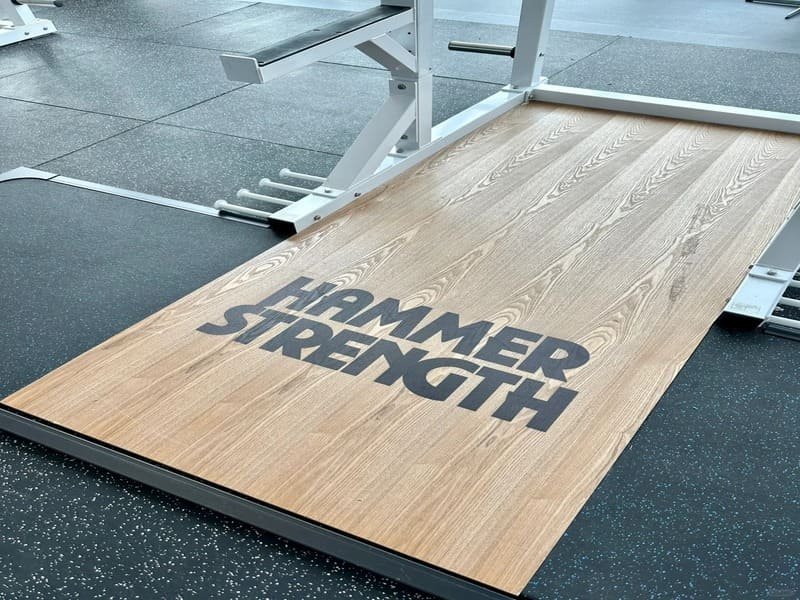 Een goed verlichte fitnessruimte thuis met veelzijdige zwarte in elkaar grijpende rubberen tegelvloeren.